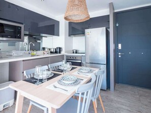 A modern kitchen with a dining area, equipped with stainless steel appliances, a large refrigerator, and a dining table set for four.