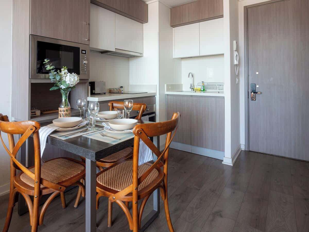 A modern kitchen with built-in appliances, a dining table with chairs, and a small island with a sink.