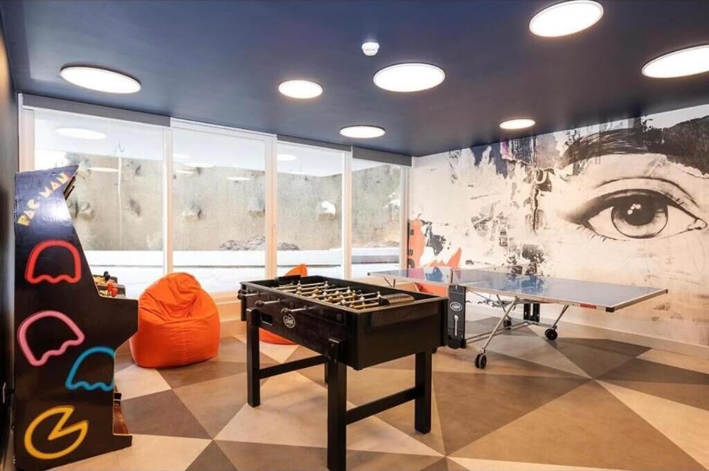 A room with a foosball table, a ping pong table, and a bean bag chair.