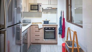 Una cocina compacta con electrodomésticos de acero inoxidable, muebles de madera, un microondas y un horno pequeño.