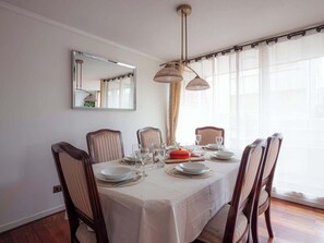 A dining room with a table set for four, chairs, a mirror, and a window with curtains. - Central Viña Walkable Apartment Near Beach (Viña del Mar)
