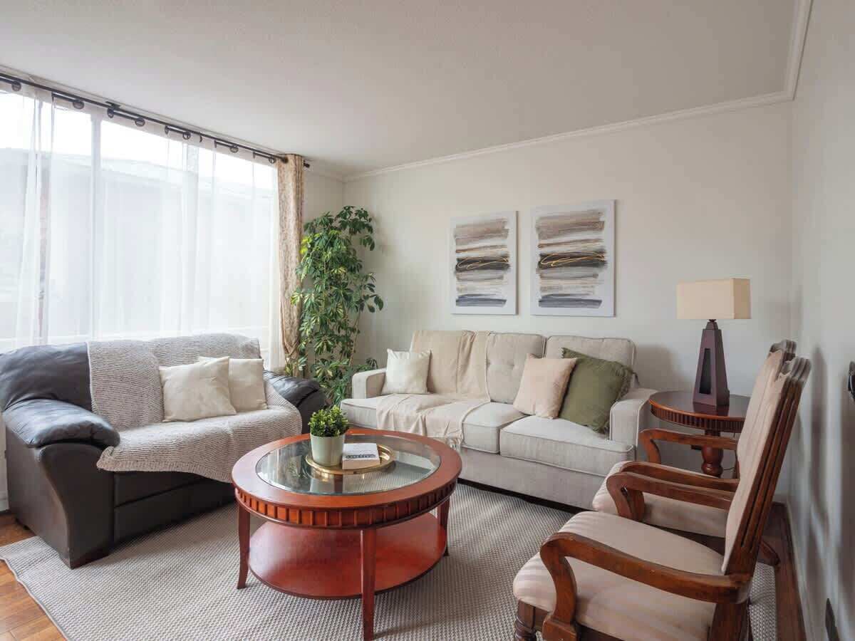 A living room with a grey sofa, a beige sofa, a round coffee table, and a wooden chair.