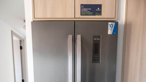 Ein Edelstahl-Kühlschrank mit digitaler Anzeige, ein Holzschrank darüber und ein Fliesenboden.