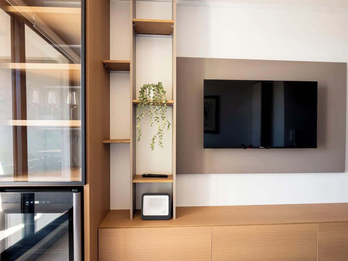 A modern kitchen with a built-in oven, a microwave, and a TV mounted on the wall.