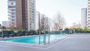Ein Swimmingpool mit Liegestühlen, umgeben von hohen Wohnhäusern.