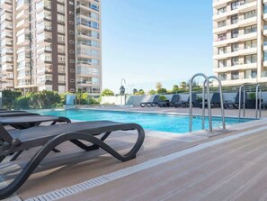 Una piscina amb gandules i vista de blocs d'apartaments alts.