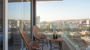 A balcony with two wicker chairs and a small table, overlooking a cityscape. - Apartamento 1 Habitación Quinta Vergara (Viña del Mar)