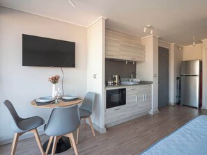A modern kitchen with a dining area, a flat-screen TV, and a refrigerator. - Apartamento 1 Habitación Quinta Vergara (Viña del Mar)