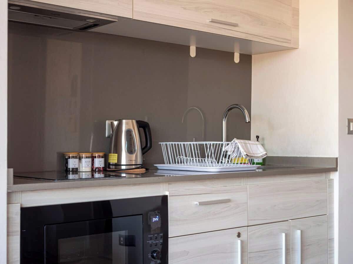 Una cocina moderna con lavavajillas integrado, hervidor y escurreplatos blanco.