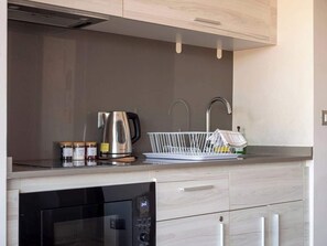 Eine moderne Küche mit integriertem Geschirrspüler, Wasserkocher und einem weißen Geschirrgestell.