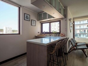 Eine moderne Küche mit Kochinsel, Barhocker und Blick auf die Stadt.