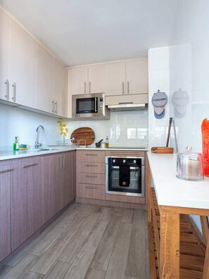 Eine moderne Küche mit Edelstahlgeräten, Holzschränken und einer weißen Arbeitsplatte.