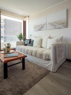 Una sala moderna con un sofá, una mesa de centro y un ventanal grande.