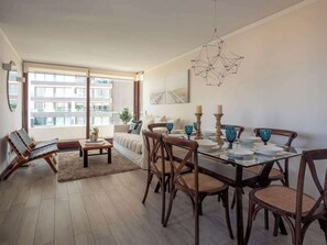A modern living room with a dining area, large windows, and a view of the city.