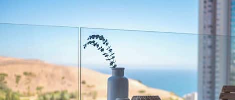 A round table with a vase and a bowl on it, overlooking a coastal landscape.