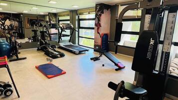 A gym with various exercise equipment, including treadmills, weights, and a bench.