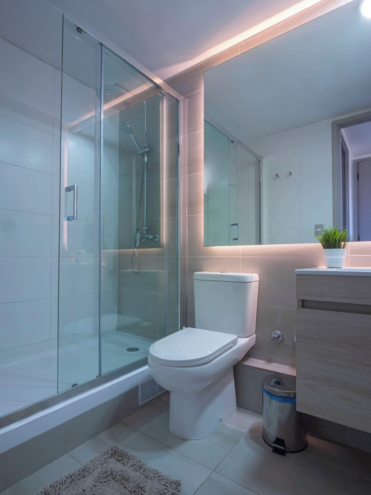 Une salle de bain moderne avec une douche à parois de verre, des toilettes, un bidet et un lavabo avec un miroir.