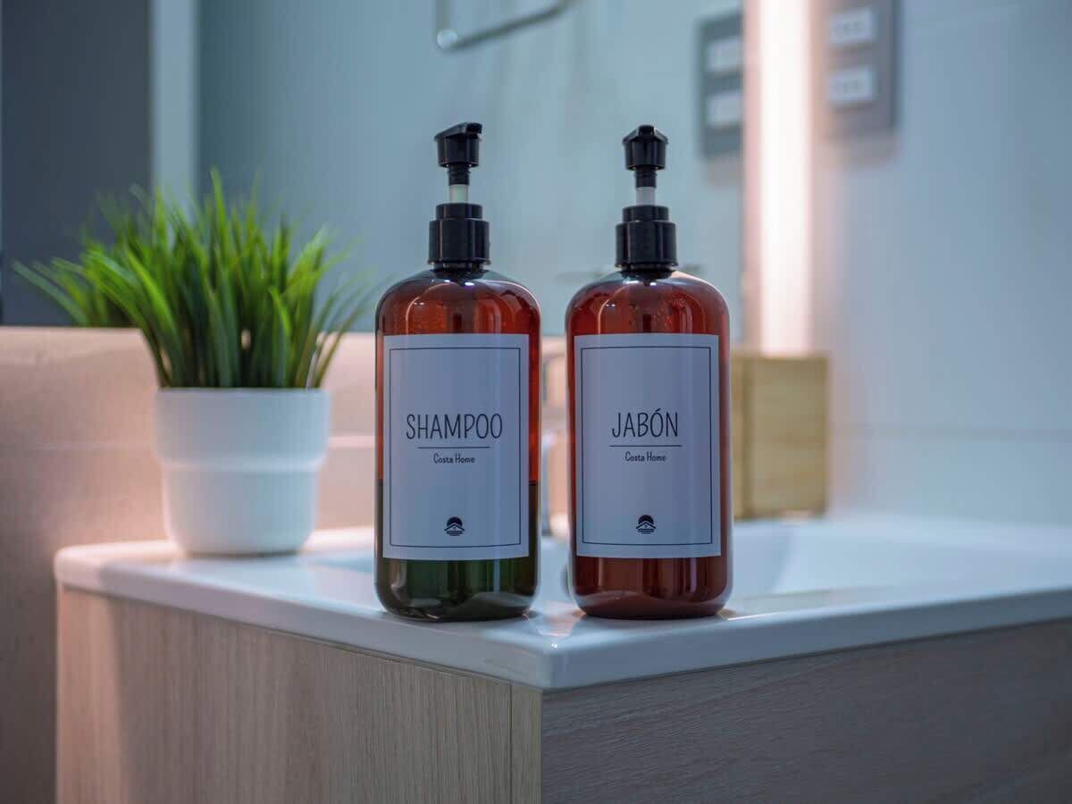 Two bottles of shampoo and jabón on a countertop.