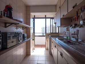 Eine schmale Küche mit Fenster, einer Mikrowelle, einem Toaster und einem Spülbecken.