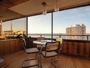 Ein Balkon mit Tisch und Stühlen, mit Blick auf Stadt und Meer.