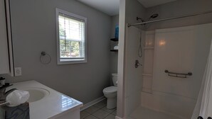 Een badkamer met douche, toilet en wastafel.
