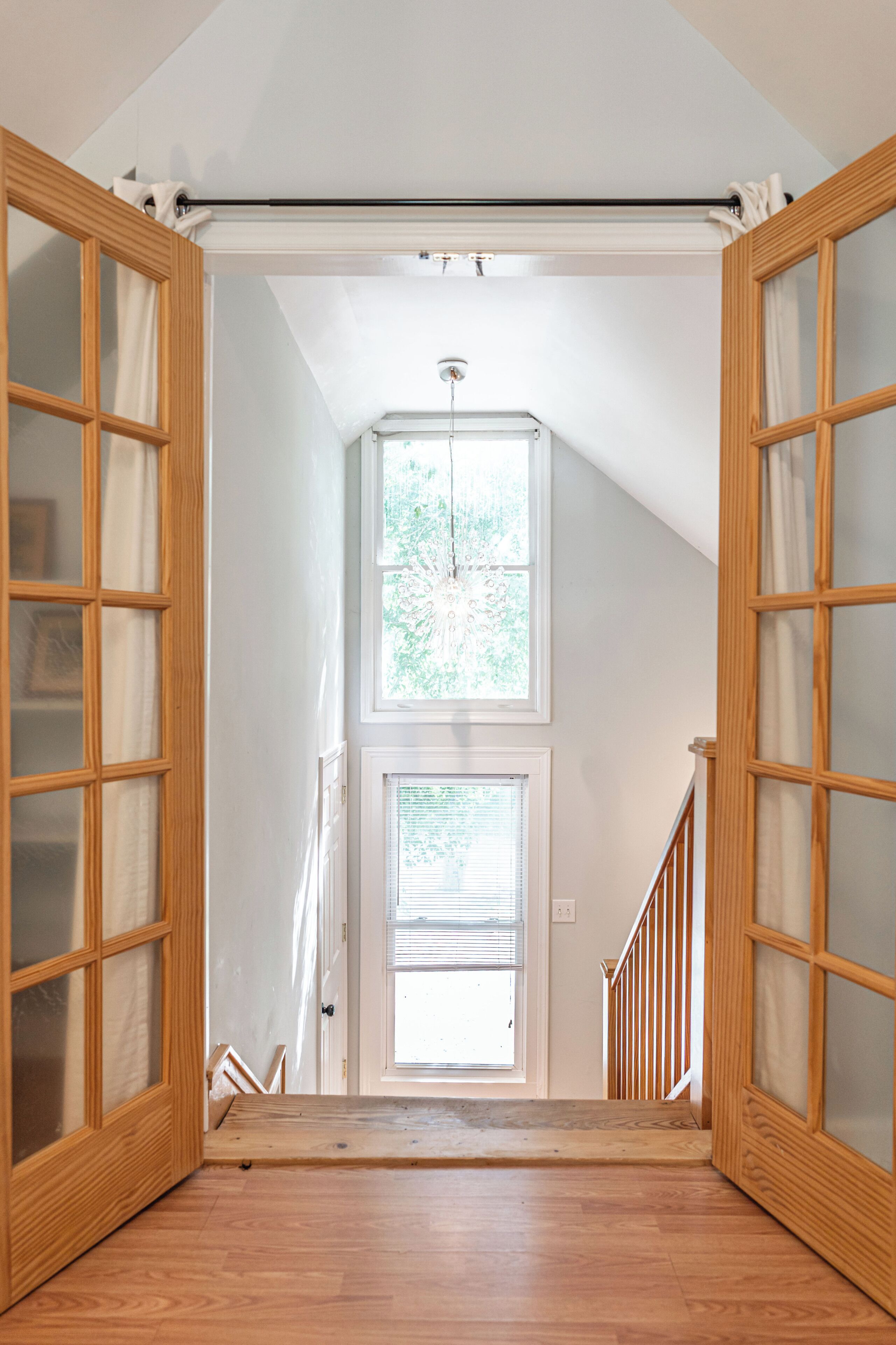 A staircase leading to a second floor with wooden doors and a window.