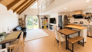 Une cuisine moderne dotée d’un grand îlot central, un coin repas avec une table et des chaises en bois, et un espace de détente avec un canapé et un téléviseur.