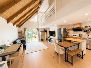 A modern kitchen with a large island, a dining area with a wooden table and chairs, and a living area with a sofa and a TV. - Architectural Loft Home. Private Access with yard (La Cañada Flintridge)