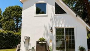 Une maison blanche à deux étages, dotée d’une grande fenêtre et d’une porte-fenêtre coulissante.