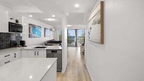 A modern kitchen with white cabinetry, a marble countertop, and a view to the outdoors. - One Bedroom Mediterranean Escape at Burleigh (Gold Coast)