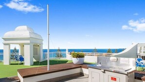 An outdoor deck with a barbecue area, a gazebo, and a view of the sea. - One Bedroom Mediterranean Escape at Burleigh (Gold Coast)