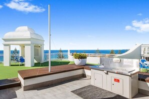 An outdoor deck with a barbecue area, a gazebo, and a view of the sea. - One Bedroom Mediterranean Escape at Burleigh (Gold Coast)
