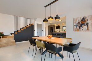 A modern kitchen with a dining area, featuring a wooden table, black chairs, and pendant lighting. - Villa Duplich (Istria - Šajini) (Šajini)
