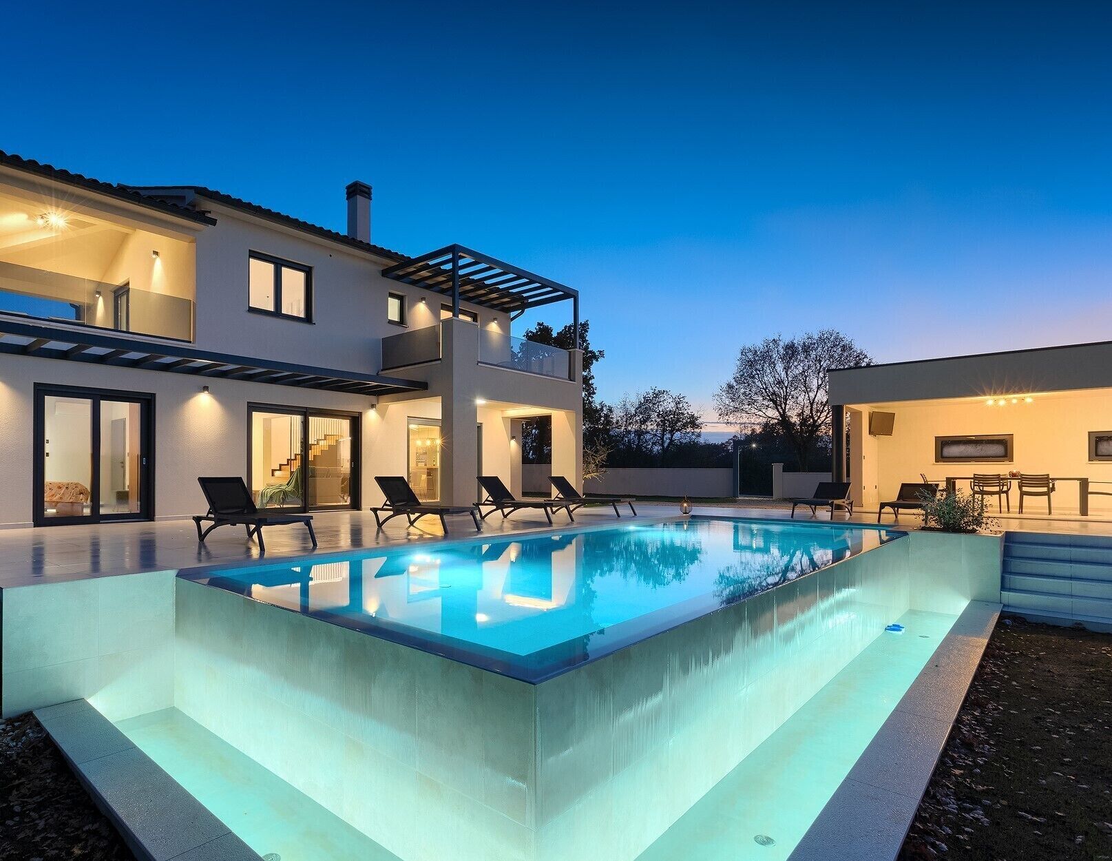 A modern house with a swimming pool, outdoor seating, and a covered patio area.