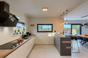 Eine moderne Küche mit Kochinsel, eingebautem Backofen und Fenster mit Blick auf eine schöne Landschaft.