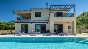 Et toetagers hus med swimmingpool, udendørs siddepladser og et pergola.