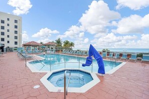 A pool area with multiple swimming pools, lounge chairs, and a building in the background. - Cozy 1-bedroom apartment with AC in fantastic Hollywood (Hollywood)