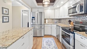 A modern kitchen with stainless steel appliances, white cabinetry, and a patterned backsplash. - Coastal Condo w/ Panoramic Water Views (St. Petersburg)