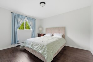 A bedroom with a bed, a nightstand, a lamp, and a window with curtains. - 4BR Family Retreat in Surrey (Surrey)