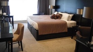 Una habitación de hotel moderna con una cama grande, mesitas de noche, un escritorio y una silla.