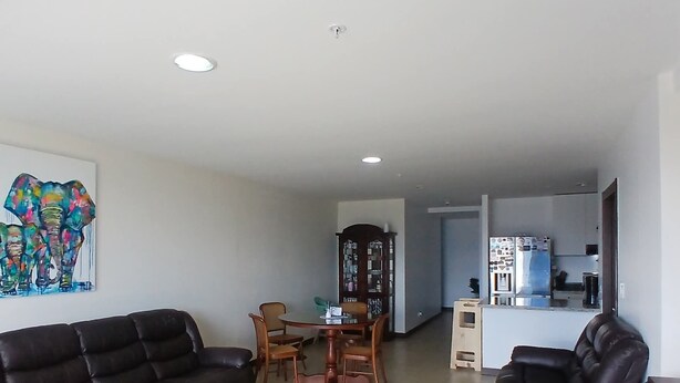 Sala de estar con sofá, mesa de comedor, sillas y una zona de cocina con electrodomésticos.