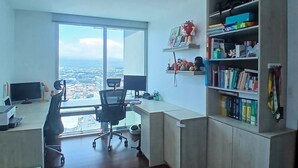 Un espacio de oficina moderno con un escritorio grande, monitores de computadora, una silla y una estantería.