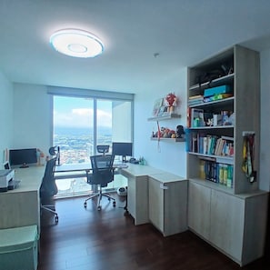 Ein moderner Arbeitsplatz mit großem Schreibtisch, Computermonitoren, einem Stuhl und einem Bücherregal.