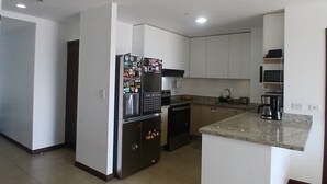 Una cocina moderna con una isla central, electrodomésticos integrados y amplio espacio en las encimeras.