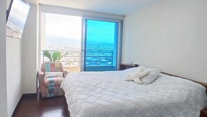 Un dormitorio con una cama grande, una ventana con vista a la ciudad y una lámpara de techo.