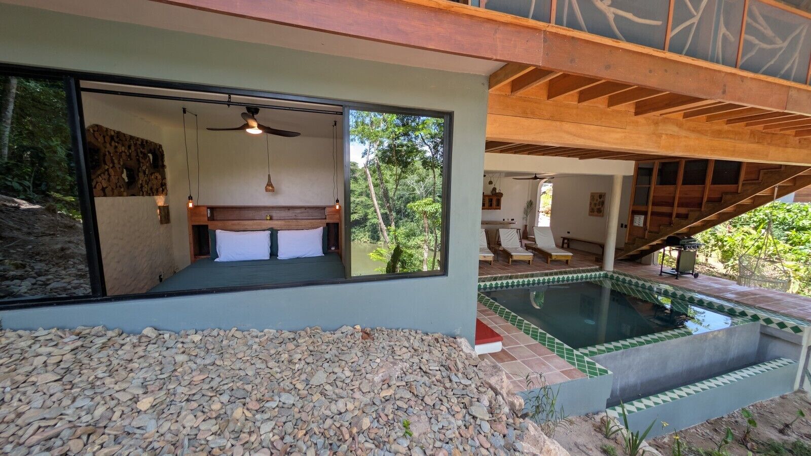 A modern bedroom with a large bed, a ceiling fan, and a view of a swimming pool.