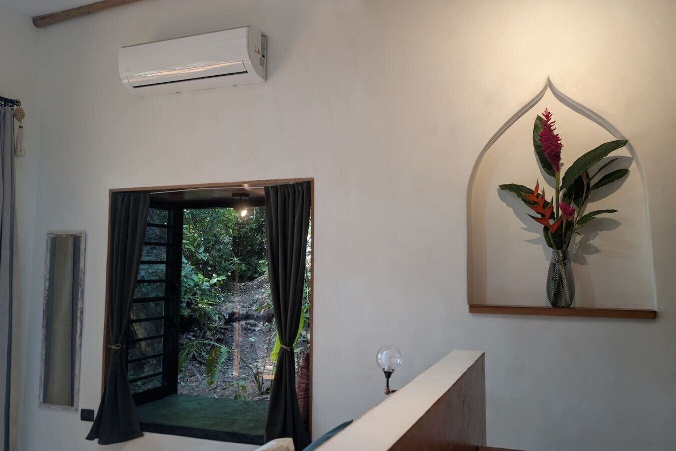 Un appareil de climatisation, une porte-fenêtre donnant sur un paysage naturel et un élément décoratif fixé au mur.