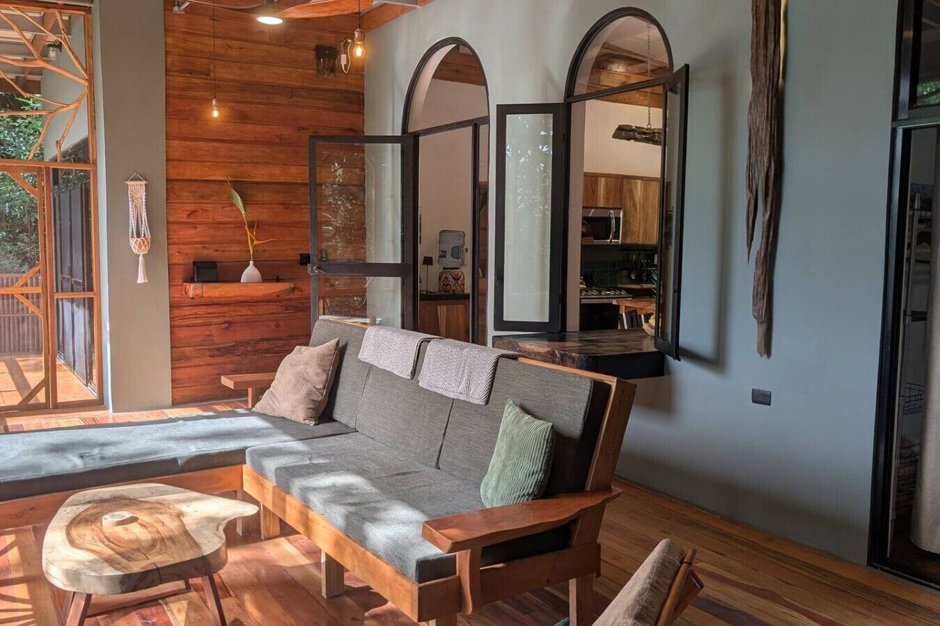 Un salon moderne avec un canapé en bois, une petite table en bois et un grand miroir.