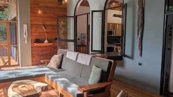 Un salon moderne avec un canapé en bois, une petite table en bois et un grand miroir.