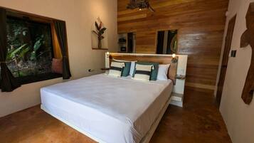 A bedroom with a large bed, wooden walls, a window with curtains, and a plant.
